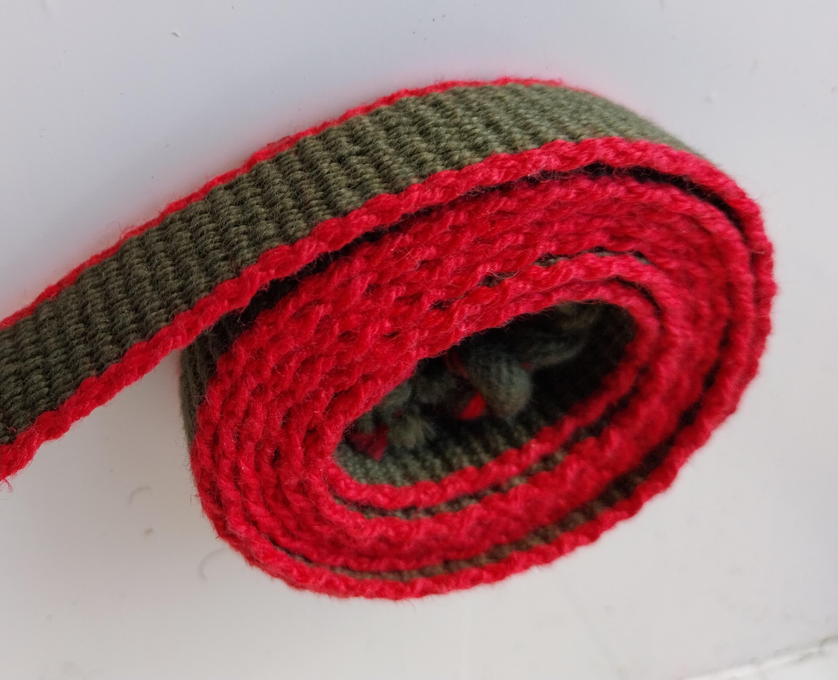 Ensfarvet grønt bånd med røde kanter.
Cottolin.